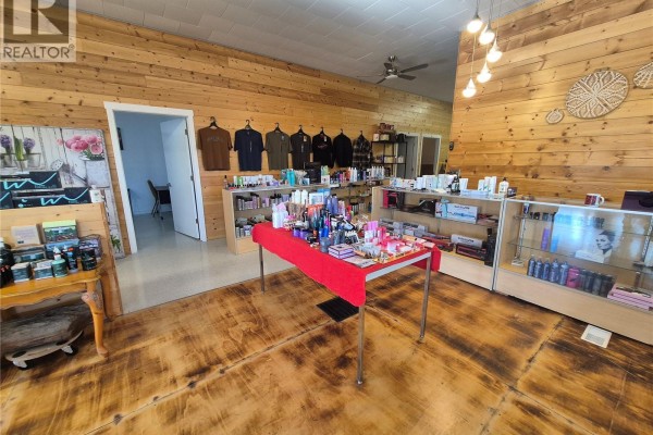 Interior view of a retail space with wood-paneled walls, display shelves, and a red-covered table. - 220 Main Street, Bengough