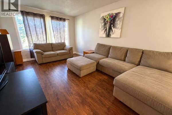 Living room with large sectional sofa, ottoman, two sofas, and large window with sheer curtains. - 220 Mcgill Boulevard W, Lethbridge