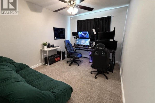 Home office or gaming room with multiple monitors, gaming chairs, and a green couch. - 220 Mcgill Boulevard W, Lethbridge