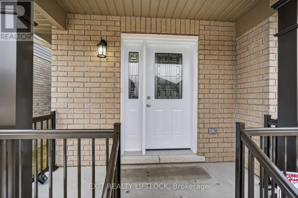 Close-up of the white front door with decorative glass panels and brick exterior. - 220 O'neil Street, Peterborough