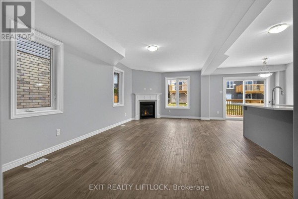 Living room with a gas fireplace, large windows, and wood-look flooring. - 220 O'neil Street, Peterborough