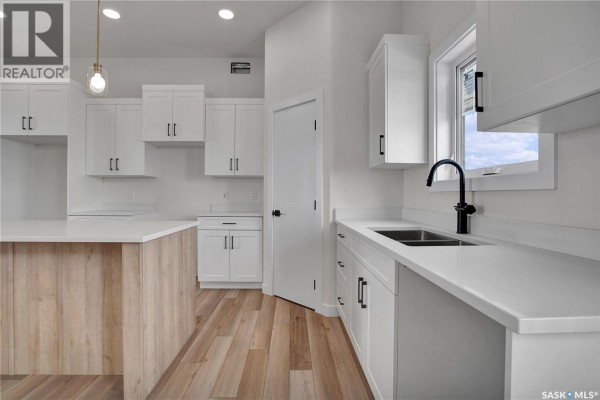 Spacious room with hardwood flooring, large window, and staircase access - 220 Veterans Drive, Warman