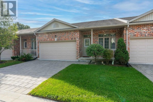 Front view of a brick townhouse with a beige garage door, covered porch, and walkway. - 220 Walnut Street, Lucan Biddulph