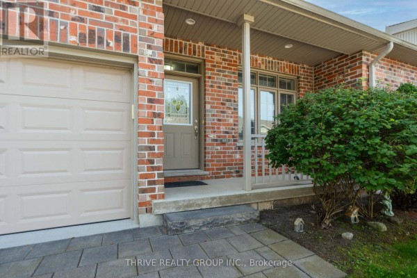 Close-up of a townhouse front door with a glass insert, flanked by a garage and shrubbery. - 220 Walnut Street, Lucan Biddulph