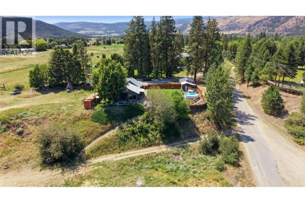 Aerial view of houses and a barn on a grassy slope beside a body of water. - 2200 Almond Gardens Road, Grand Forks