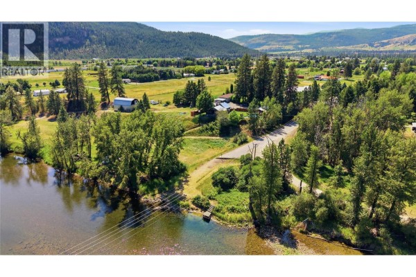 Backyard with a pond, rock garden, covered seating area, and a wooden deck overlooking the water. - 2200 Almond Gardens Road, Grand Forks