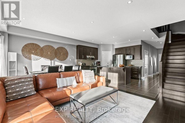 Living room with a large sectional sofa, coffee table, wall-mounted TV, and dark wood floors. - 2200 Nantes Street, Ottawa