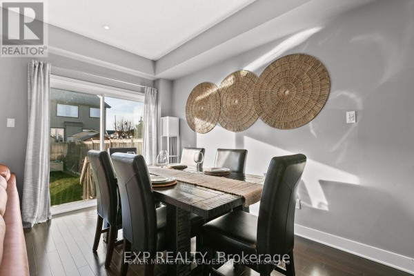 Open-concept living and dining area with a sectional sofa, dining table, and dark cabinetry. - 2200 Nantes Street, Ottawa