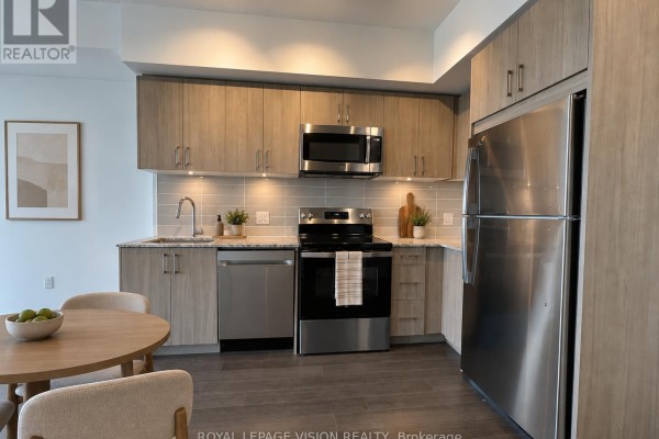 Kitchen with light wood cabinets, stainless steel appliances, and a round dining table. - 2201 - 4010 Eglinton Avenue W, Toronto