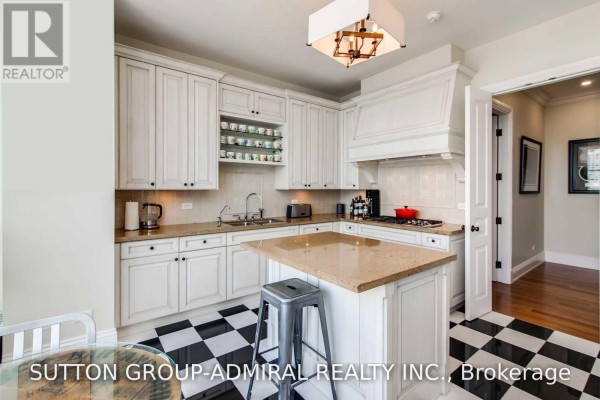 White kitchen with island, granite counters, checkered floor, and modern appliances. - 2202 - 183 Wellington Street W, Toronto