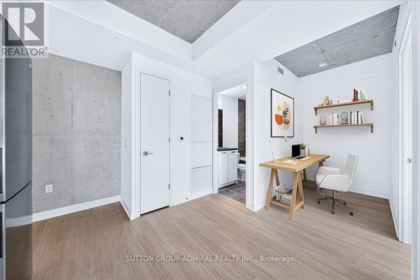 Modern lobby with concrete walls, black seating, and a reception desk with a neon sign. - 2202 - 284 King Street E, Toronto