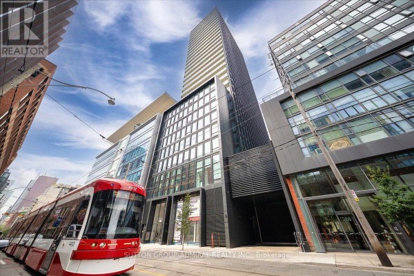 Building corridor with elevators, black doors numbered 22, 23, and 2203, and patterned carpet. - 2202 - 284 King Street E, Toronto