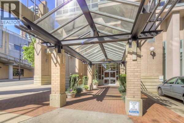 Covered entrance to the apartment building with brick pillars, glass roof, and potted plants. - 2203 930 Cambie Street, Vancouver