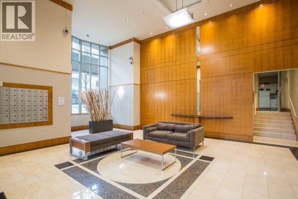 Interior lobby with mailboxes, sofas, a coffee table, and wood-paneled walls. - 2203 930 Cambie Street, Vancouver