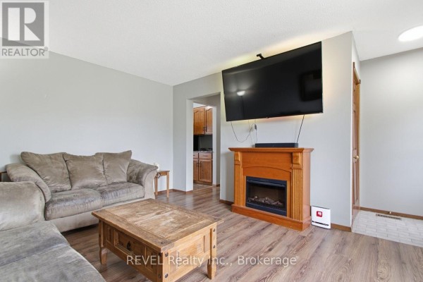 Living room with sectional sofa, electric fireplace, mounted television, and view into kitchen. - 2203 Stevensville Road, Fort Erie