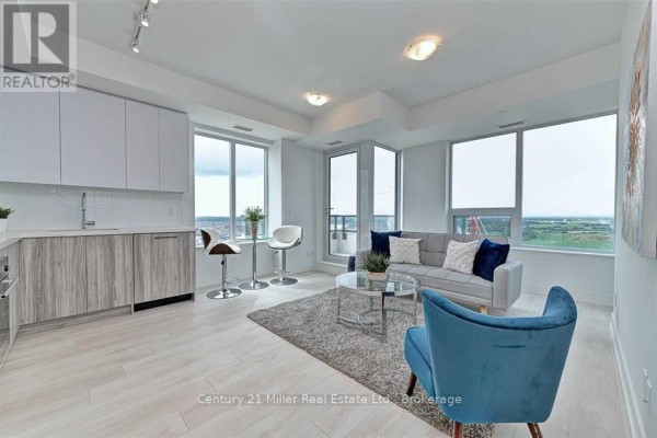Apartment living area and kitchen with large windows, balcony doors, and city views. - 2204 - 297 Oak Walk Drive, Oakville