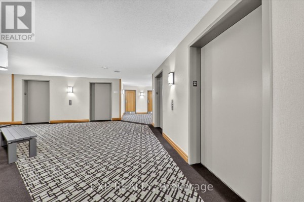 Elevator lobby with grey doors, modern carpet, bench, and wood trim on the walls. - 2204 - 7 Concorde Place, Toronto