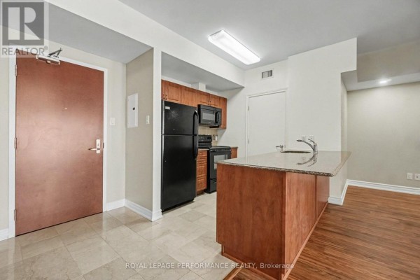 Kitchen with dark appliances, wooden cabinets, granite countertops, and tile flooring. - 2205 - 234 Rideau Street, Ottawa