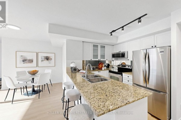 Living room with large windows, neutral-colored sofa and armchair, and city view. - 2205 - 761 Bay Street, Toronto