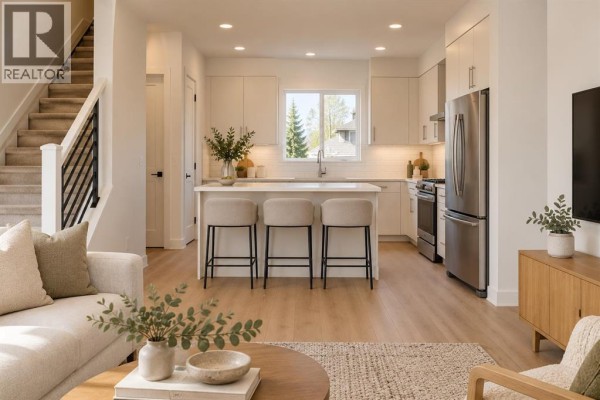 Open concept kitchen and living area with white cabinets, island, and stainless steel appliances. - 2205 1 Street Ne, Calgary