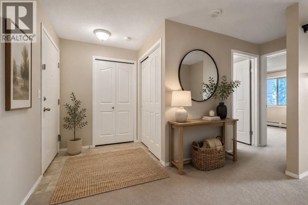 Apartment entryway with console table, mirror, and double closet doors. - 2206, 16969 24 Street Sw, Calgary
