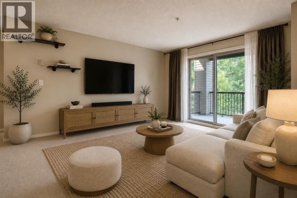 Living room with sectional sofa, coffee table, entertainment unit, and balcony access. - 2206, 16969 24 Street Sw, Calgary