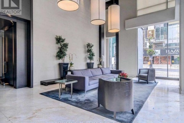 Building lobby with a grey sofa, chairs, blue rug, and marble floors. - 2206 - 18 Yorkville Avenue, Toronto