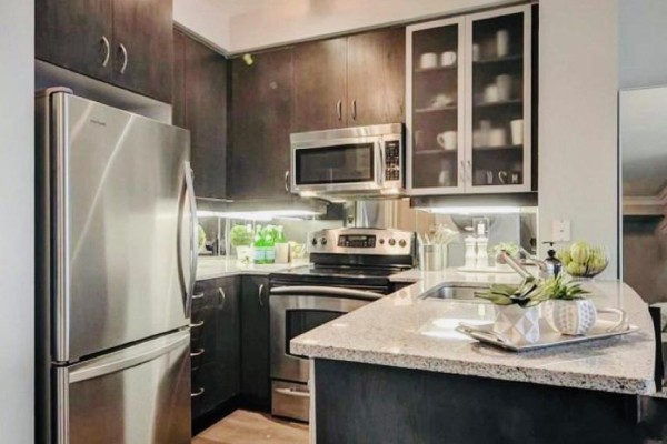 Kitchen with dark wood cabinets, stainless steel appliances, and granite countertops. - 2206 - 18 Yorkville Avenue, Toronto