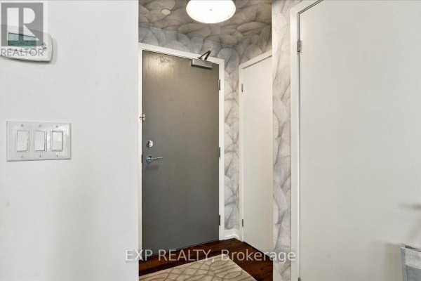 Apartment entrance hallway with gray door, white doors, and patterned wallpaper. - 2206 - 21 Widmer Street, Toronto