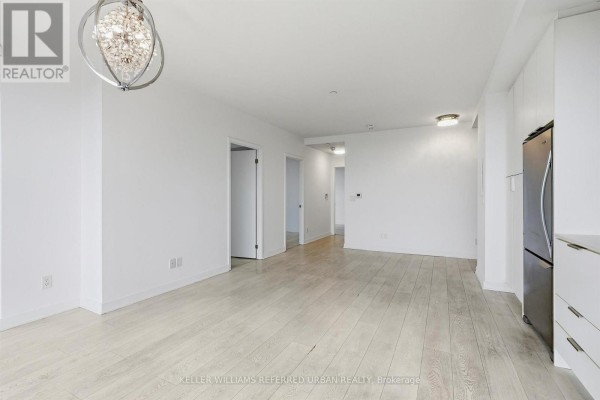 Living area with white walls, light wood floors, and a view into the hallway. - 2207 - 6 Sonic Way, Toronto