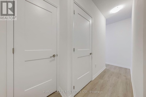 Apartment hallway with two white doors and light wood laminate flooring. - 2209 - 25 Holly Street, Toronto