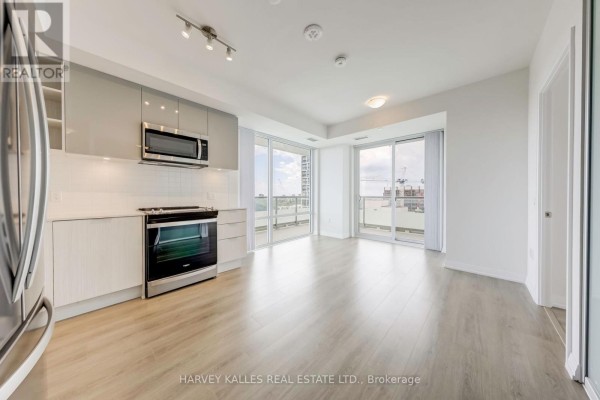 Open concept living area with kitchen, featuring stainless steel appliances and balcony access. - 2209 - 25 Holly Street, Toronto