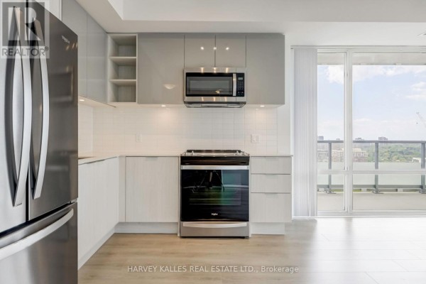 Modern kitchen with grey and white cabinets, stainless steel stove, and tiled backsplash. - 2209 - 25 Holly Street, Toronto