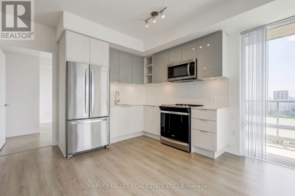 View of the apartment kitchen with stainless steel refrigerator, stove, and balcony access. - 2209 - 25 Holly Street, Toronto