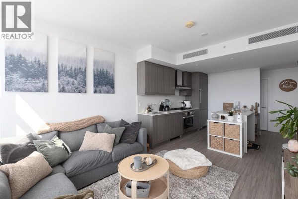 Living room and kitchen area with gray sectional sofa, wood cabinets, and island. - 2209 2351 Beta Avenue, Burnaby