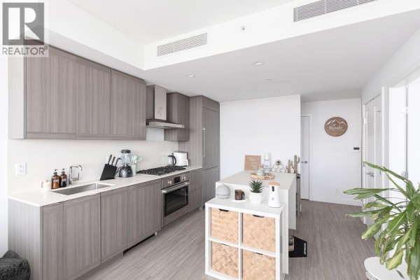Modern kitchen with gray cabinets, white countertops, stainless steel appliances, and island. - 2209 2351 Beta Avenue, Burnaby