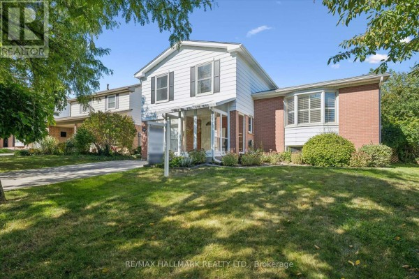 Side view of a two-story house with brick and white siding, and a large green lawn. - 2209 Buttonbush Crescent, Mississauga