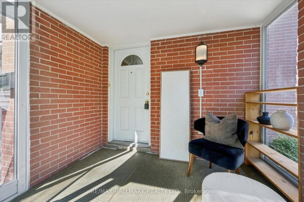 Interior view of a screened-in porch with brick walls, a white door, a chair, and shelving. - 2209 Buttonbush Crescent, Mississauga