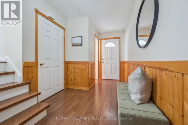 Interior view of a hallway with wood-paneled walls, a staircase, and hardwood floors. - 2209 Buttonbush Crescent, Mississauga