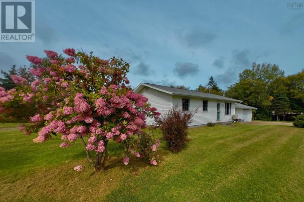 Side view of the white bungalow with a large pink flowering shrub in the foreground. - 2209 Lingan Road Road, Lingan