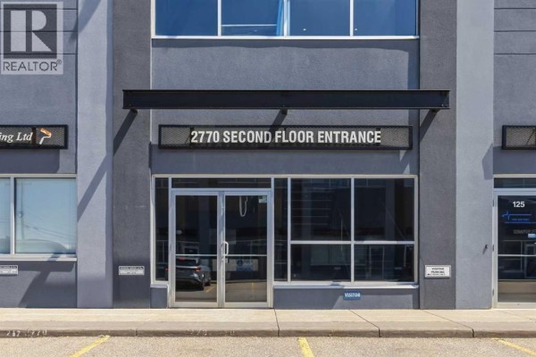 Double glass doors of the second floor entrance at 2770, with signage above and parking lot in front. - 221, 2770 3 Avenue Ne, Calgary