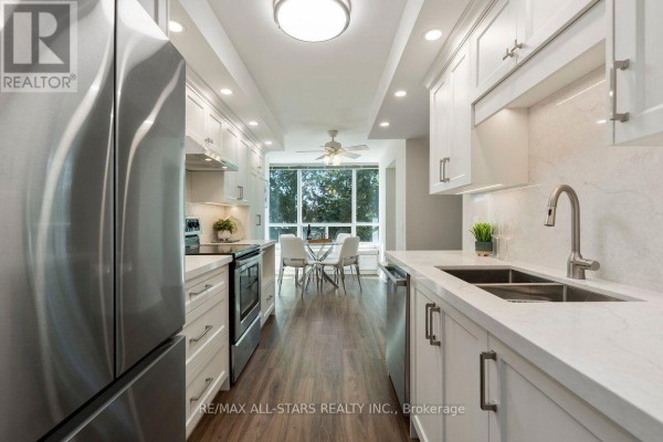 Modern kitchen with stainless steel appliances, white cabinets, and quartz countertops. - 221 - 85 The Boardwalk Way, Markham