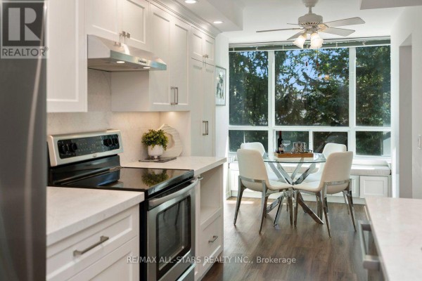 Kitchen with white cabinets, stainless steel appliances, and dining area with large window. - 221 - 85 The Boardwalk Way, Markham