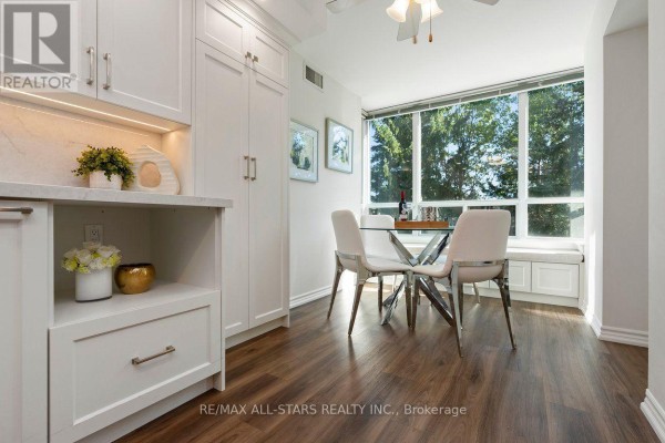 White kitchen cabinets, stainless steel appliances, and dining area with bay window. - 221 - 85 The Boardwalk Way, Markham