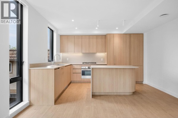 Bright kitchen with light wood cabinetry, stainless steel appliances, and a central island. - 221 2820 Nanaimo Street, Vancouver