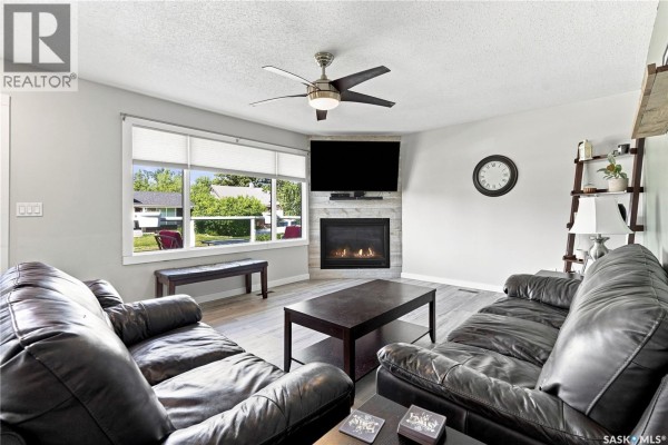 Living room with two dark leather sofas, a gas fireplace with stone surround, and a ceiling fan. - 221 Francis Street, Sedley