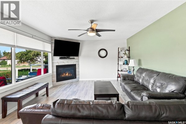 Living room with dark leather sofas, a gas fireplace with stone surround, and a light green accent wall. - 221 Francis Street, Sedley