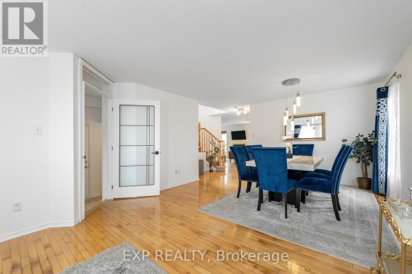 Dining room with a large rectangular table, blue velvet chairs, and pendant lights above. - 221 Northwind Street, Ottawa