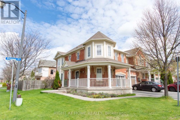 Corner view of a brick townhouse with a large covered porch and manicured lawn. - 221 Prosser Circle, Milton