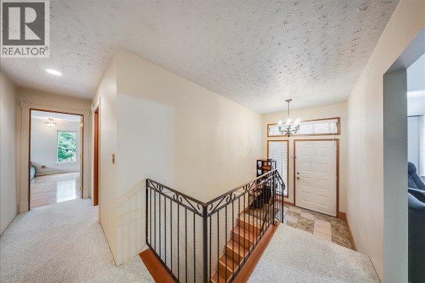Interior view of a hallway with neutral carpet, a staircase with metal railing, and an entryway. - 221 Second Avenue, Rivervale